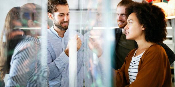 coworkers working on their analysis using a clear whiteboard