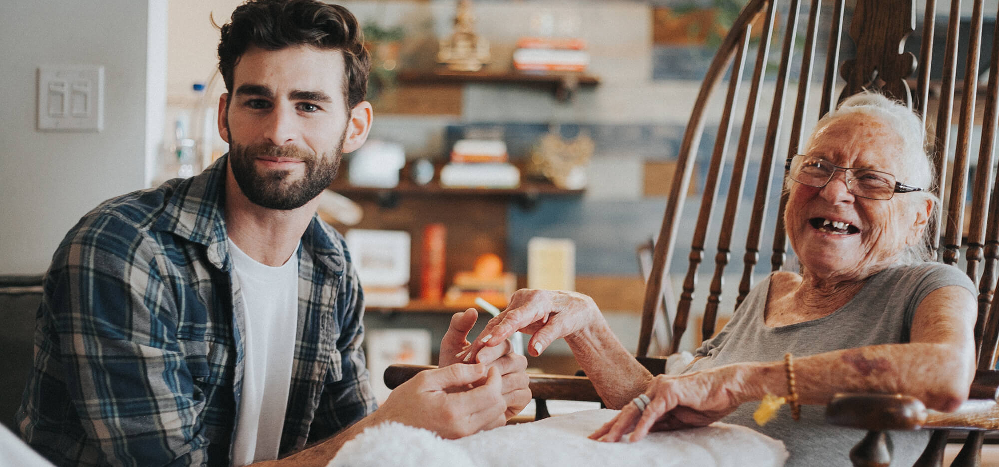 young man holding hands with elderly woman both smiling at the camera