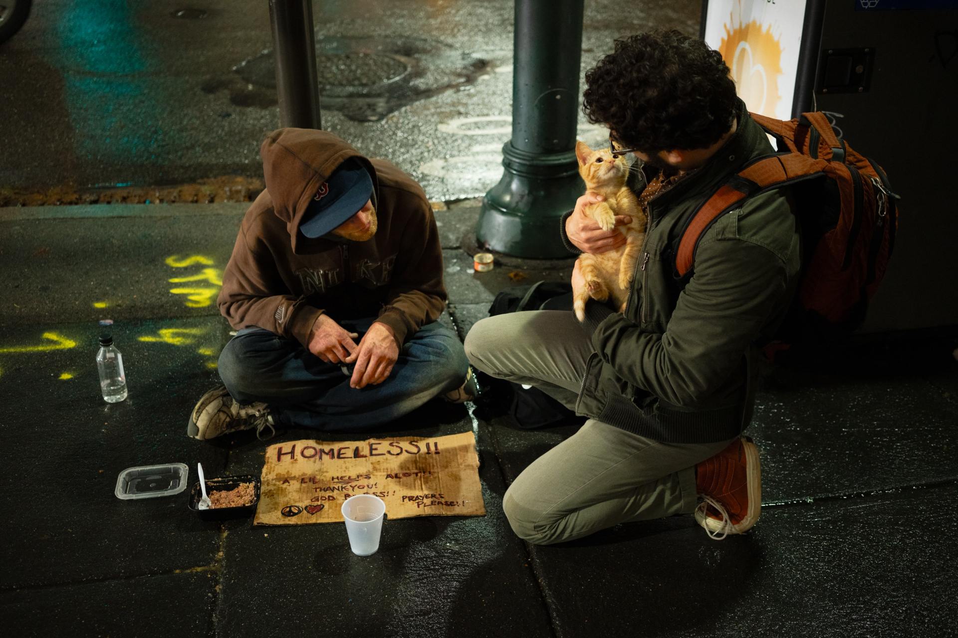 Man with a cat talking to an unhoused person