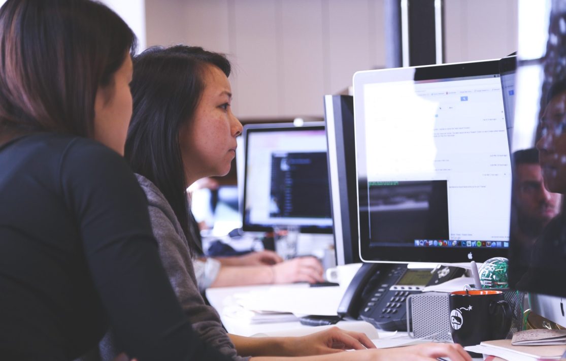 Two women looking at a desktop computer