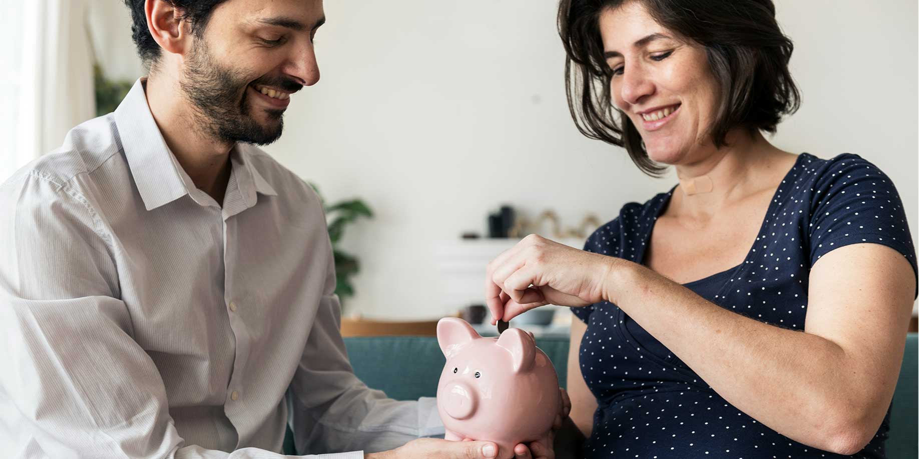 A couple putting money into a piggy bank