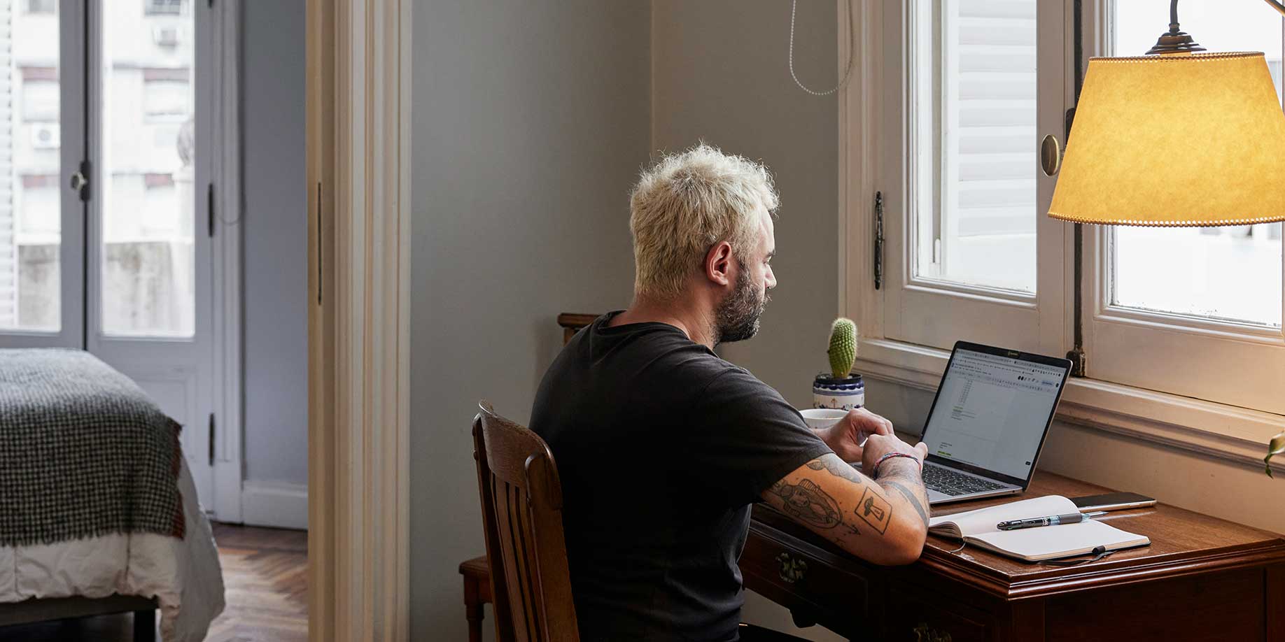 Man sitting at a laptop with an open notebook