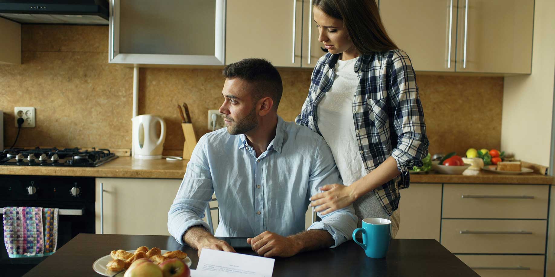 Couple looking over a bill at the kitchen table