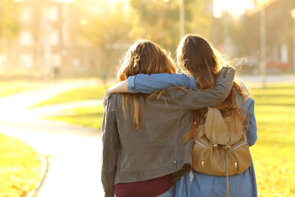 two friends walking at sunset in a park
